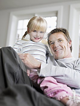 Girl Sitting On Father's Lap In House