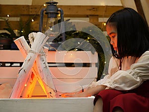 Girl sitting by the fire with camping background