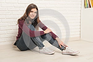 Girl sitting on the floor against a brick wall