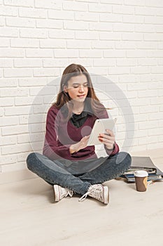 Girl sitting on the floor against a brick wall