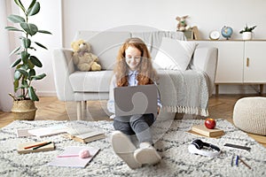 Girl sitting on floor carpet, using laptop, typing on keyboard