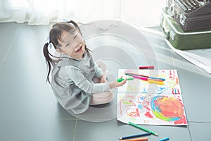 Girl sitting on the floor and drawing picture by crayon