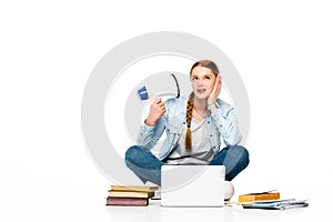 Girl sitting on floor with loudspeaker near laptop, books and copybooks