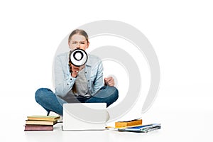 Girl sitting on floor shouting in loudspeaker near laptop, books and copybooks