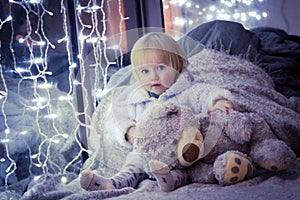 Girl sitting on the floor with a Teddy Bear on the backgroun of lights