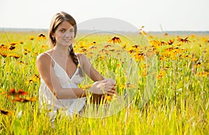 Girl is sitting on flowers meadow