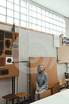 Girl sitting in gallery and looking aside