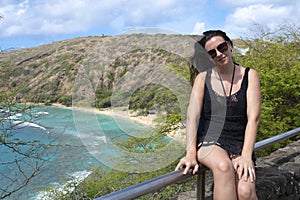 A girl sitting on a gate a front of the ocean