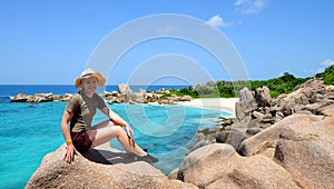 Girl sitting on granite stone near Anse Marron beach, La Digue Island, Indian ocean, Seychelles. photo