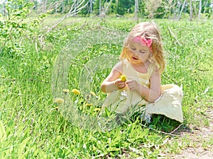 Girl sitting on grass with flowers dandelion.