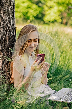 girl sitting on the grass looking at the phone. freelance. selfeducation. the concept of remote learning and outdoor photo