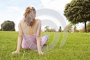Girl sitting on grass in park.