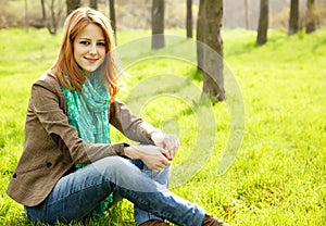 Girl sitting at green grass at park.
