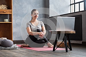 Girl sitting in Half lord of the fishes, Ardha Matsyendrasana pose at home.