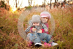 Girl Sitting With Her Baby Brother in a Field