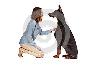 Girl sitting on her knees in front of a large black dog