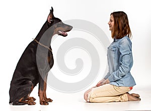 Girl sitting on her knees in front of a large black dog