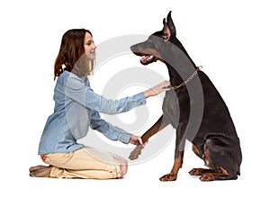 Girl sitting on her knees in front of a large black dog