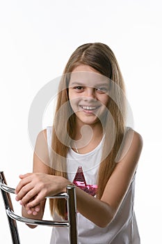 Girl sitting on a high-backed chair and smiling joyfully