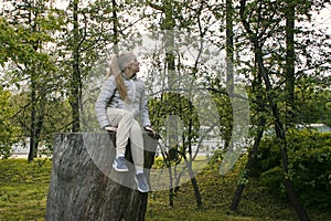 Girl sitting on a high tree stump in the park