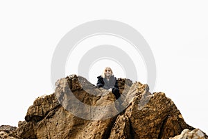A girl sitting high up on rocks