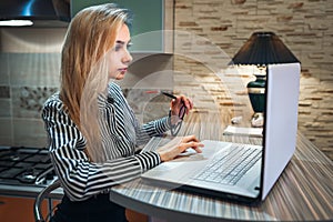 Girl sitting at home and looks attentively at a laptop