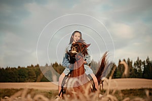 The girl is sitting on a horse running across the field