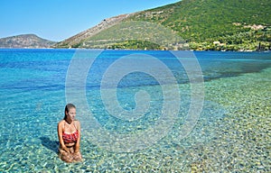 Girl sitting inside the sea at Ithaca Greece