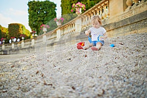 Girl sitting on a large heap of stones and playing with pebbles