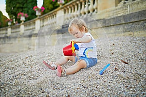 Girl sitting on a large heap of stones and playing with pebbles