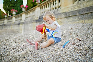 Girl sitting on a large heap of stones and playing with pebbles