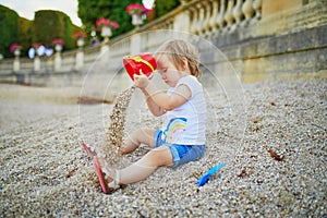 Girl sitting on a large heap of stones and playing with pebbles