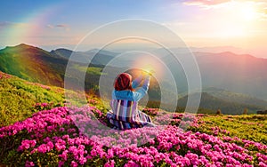 The girl sitting on the lawn among pink rhododendrons.