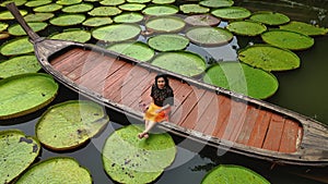 Girl sitting on a long tail boat surrounded by Queen Victoria water lilies in Phuket Thailand