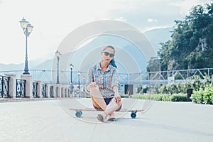 Girl sitting on longboard outdoor.