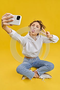 Girl sitting in lotos pose, taking selfie.