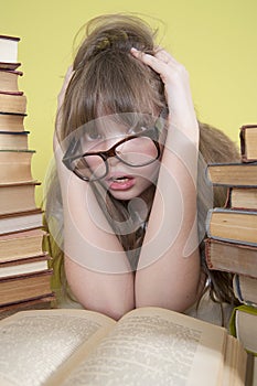 Girl sitting with lots of books and grabs his head.