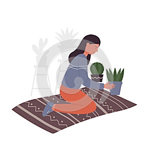 Girl sitting on mat and taking care of potted plants