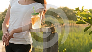 Girl sitting in a meadow with lemonade in her hands