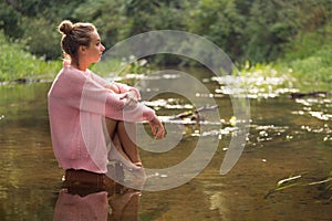 Girl sitting in the middle of the forest river