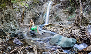 Girl sitting by the millomeri waterfalls in the troodos mountains