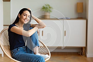 Girl Sitting In Modern Chair Smiling To Camera At Home