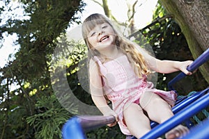 Girl Sitting on monkey bars in backyard portrait