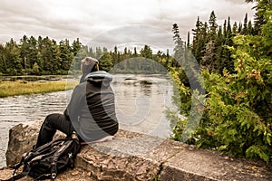 Girl sitting near Lake of two rivers in Algonquin National Park Canada Ontario natural pinetree landscape