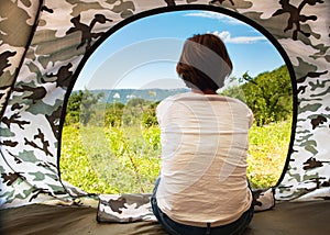 Girl sitting near open tourist tent door