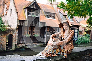 A girl is sitting next to a fabulous medieval house standing right on the canal next to the Bonifacius Bridge