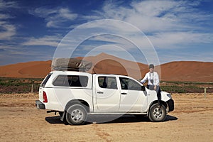 Girl sitting on an off-road car on photographic safari