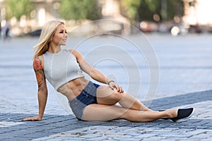 Girl sitting outdoor and showing her abdominal muscles.