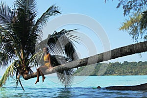 Girl sitting on a palm tree.