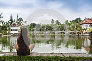 Girl sitting on pier and lookingat the river in Bali photo